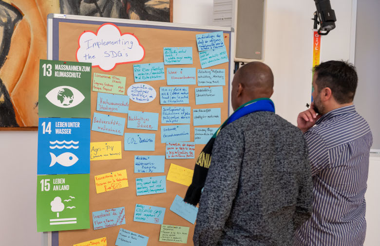 Two participants in front of a metaplan board with results of work on SDGs 13, 14 and 15.